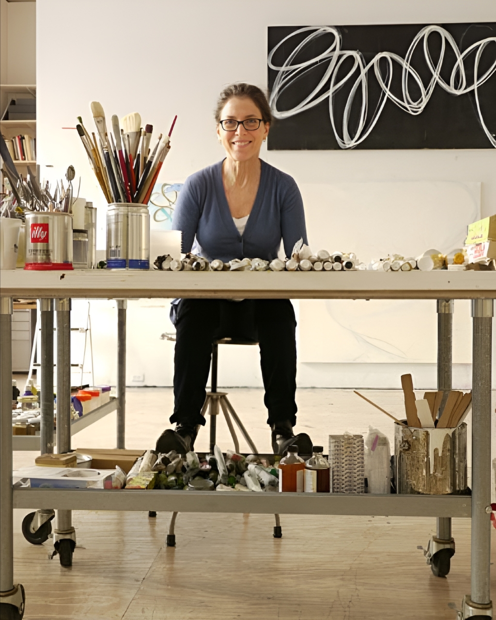 Claudia Aronow sitting in the table with painting brushes and all