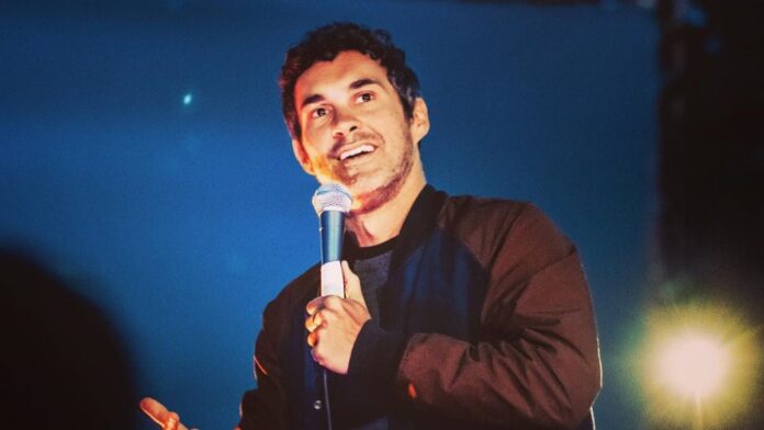 Mark Normand on the stage doing stand up comedy.